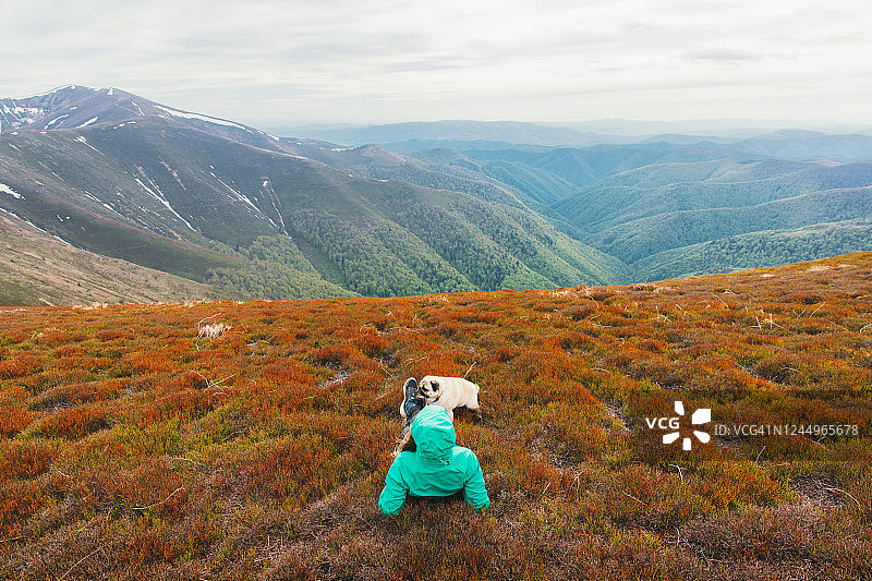 在色彩缤纷的草地上休息，欣赏山峰美景的年轻女徒步者图片素材