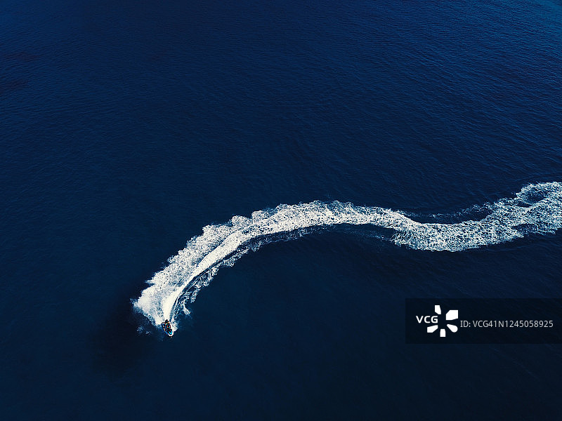 深蓝色海水中水上摩托艇的航拍视角，船只在水面划出尾迹图片素材