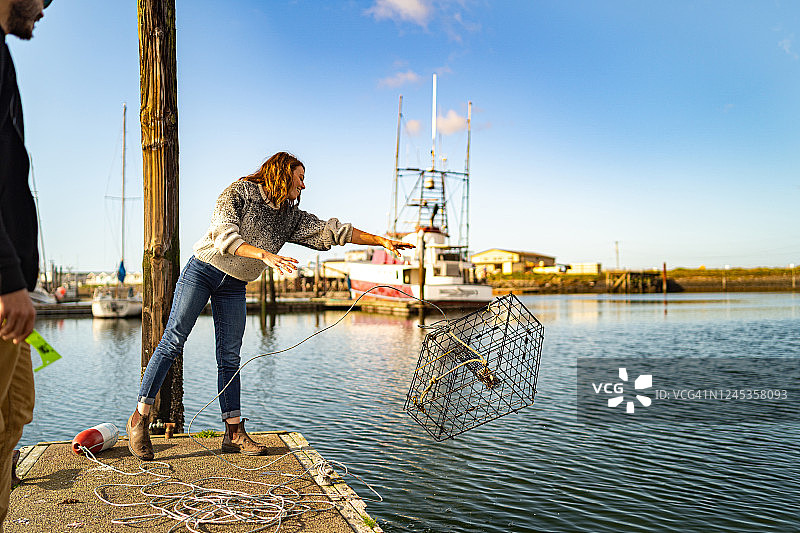 年轻女子从码头放下捕蟹网图片素材