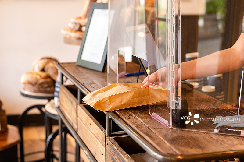 企业家通过有机玻璃防护罩传递烘焙食品以重新开业图片素材