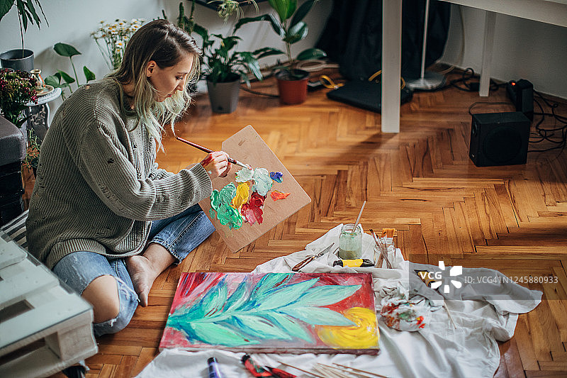 一位年轻女子在地板上绘画图片素材