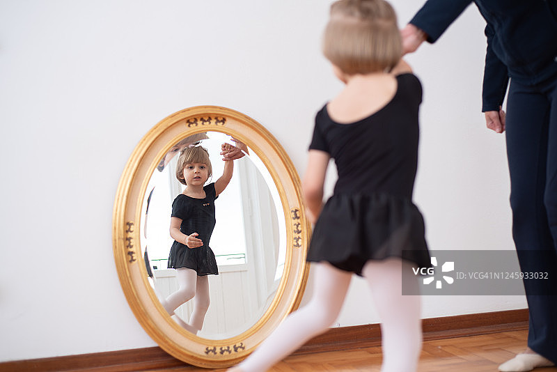 疫情隔离期间母亲在家帮助女儿练习芭蕾舞图片素材