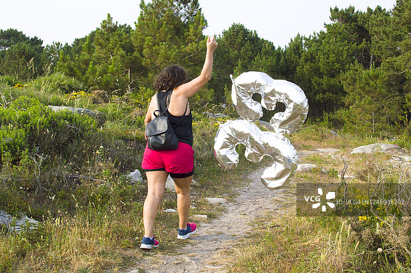 在森林中拿着33号气球行走的女人图片素材