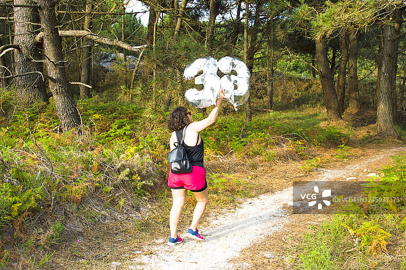 在森林中拿着33号气球行走的女人图片素材