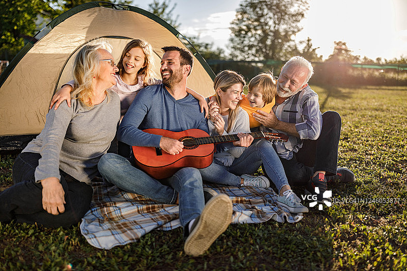 快乐的大家庭在野外露营时享受吉他音乐图片素材