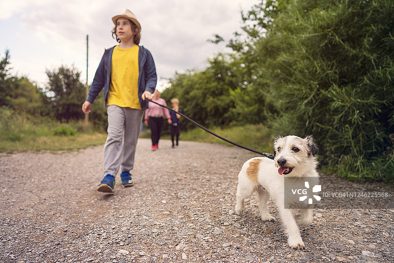 小男孩和他的狗在公园里散步图片素材