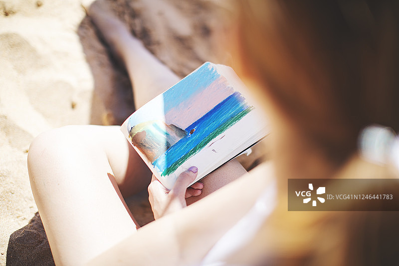 在海滩上绘画的年轻女子图片素材