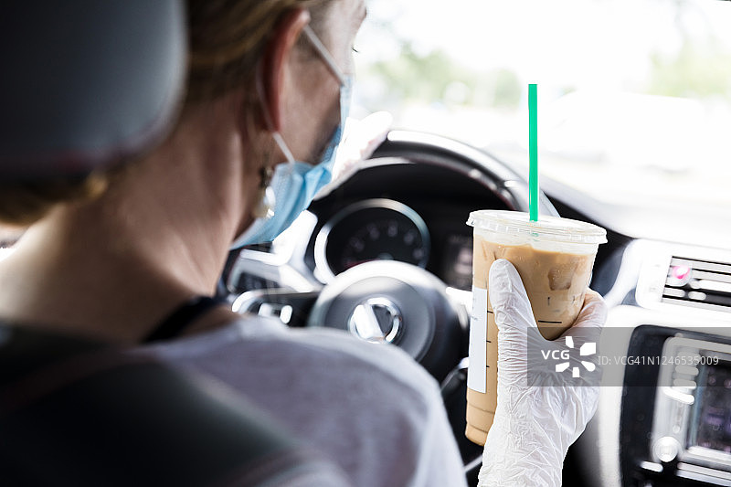 女子手持冰咖啡开车的背影图片素材