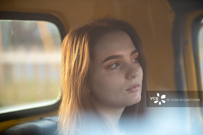 透过黄色车辆挡风玻璃拍摄的年轻女子自然状态肖像图片素材