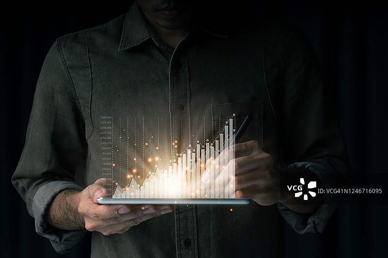 商务人士使用平板电脑分析快速增长的业务趋势，黑色背景上有上升的图表图片素材