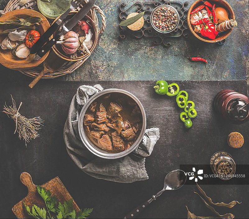 深色背景下，锅中炖肉与食材及厨具图片素材