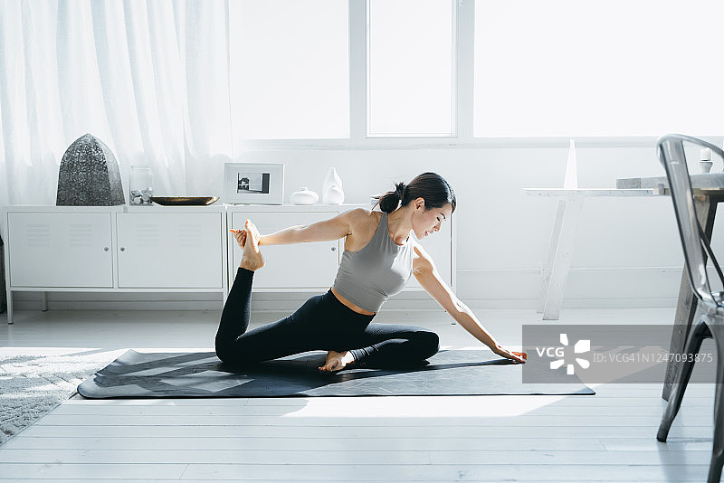 年轻的亚洲女性早晨在家中客厅练习瑜伽图片素材