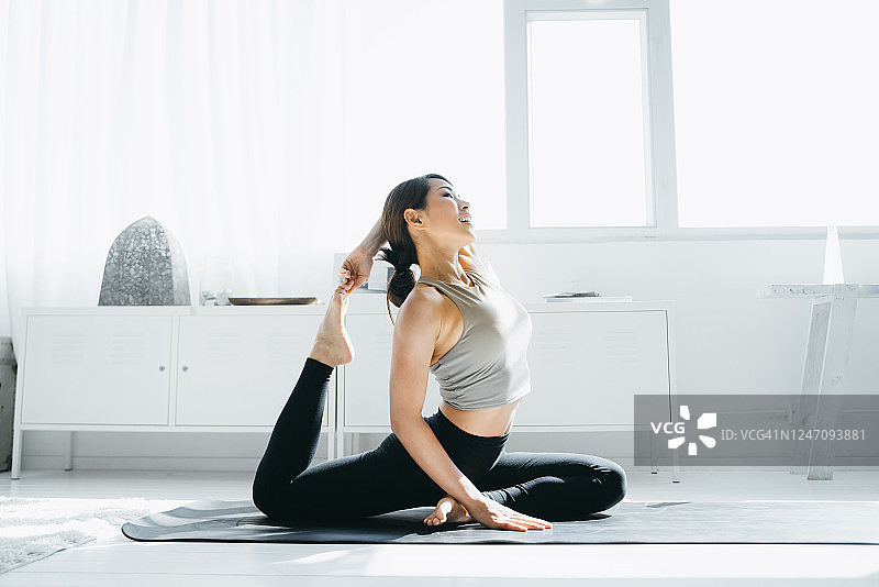年轻的亚洲女性早晨在家中客厅练习瑜伽图片素材