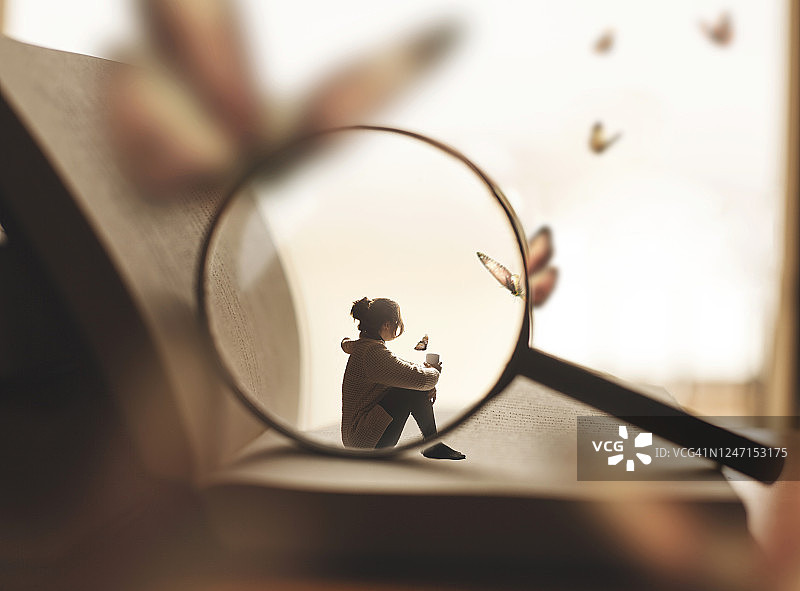 女人坐在巨型书本上喝咖啡，梦见蝴蝶图片素材