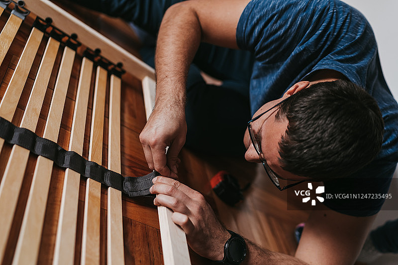 年轻男人在地板上组装家具图片素材