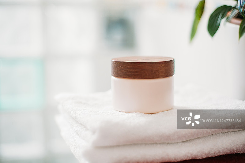 浴室毛巾上的保湿霜瓶图片素材