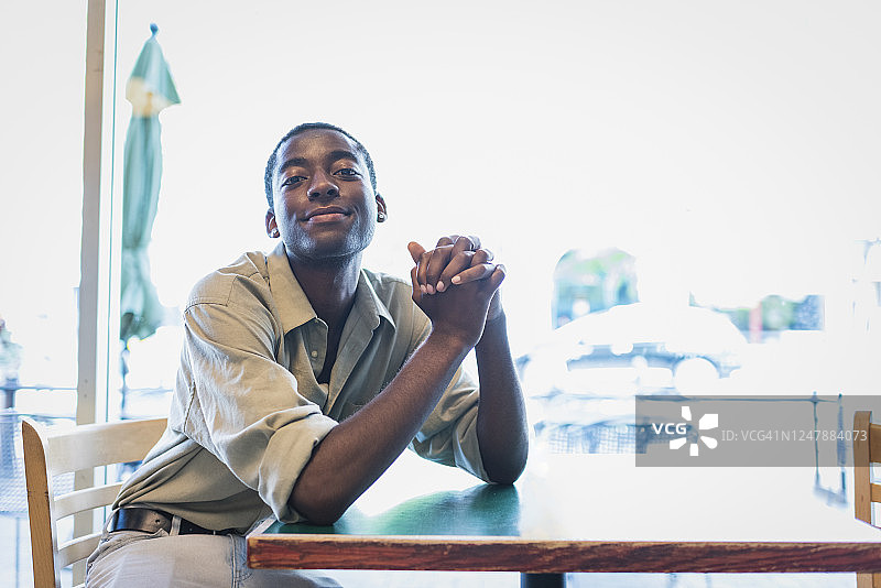 年轻男子坐在咖啡馆的桌旁图片素材