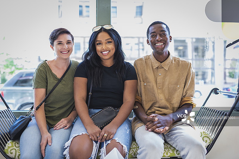 三个朋友坐在商店内的长椅上图片素材