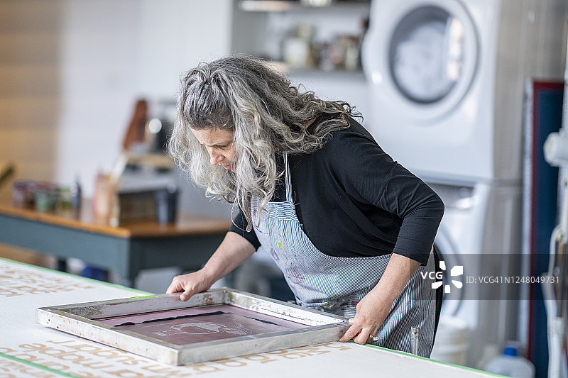 艺术家小心地将网版放在织物上图片素材