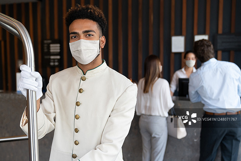 快乐的酒店服务员戴着口罩避免新冠图片素材