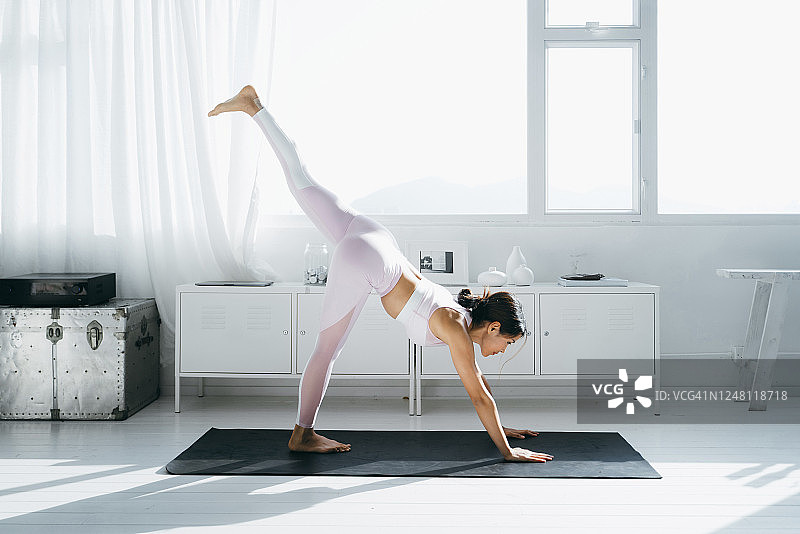 年轻的亚洲女性早晨在家中客厅练习瑜伽图片素材