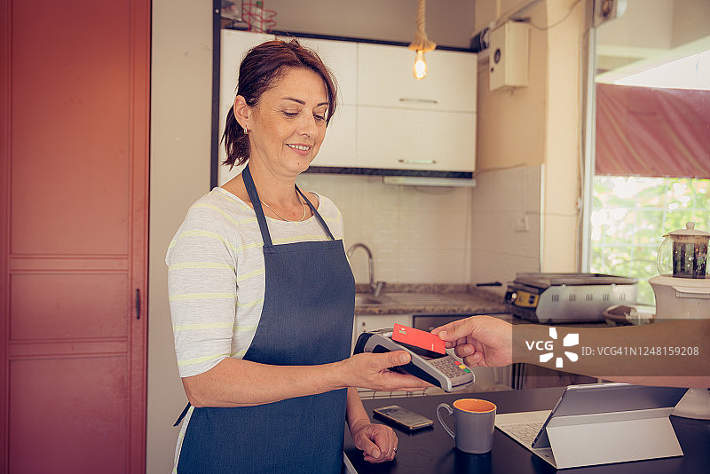 美丽的女人在咖啡馆用信用卡收款图片素材