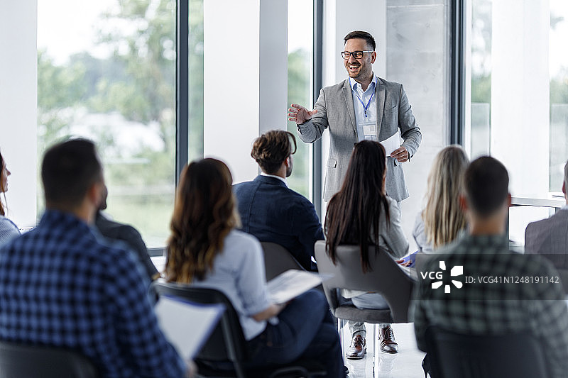 快乐的企业领导在会议室的研讨会上与同事交谈图片素材