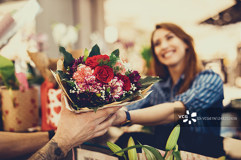 英俊的花店老板向年轻快乐的女人卖花图片素材