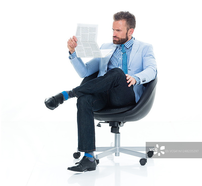 穿着衬衫在白色背景前坐着并拿着文件的年轻白人男商人图片素材