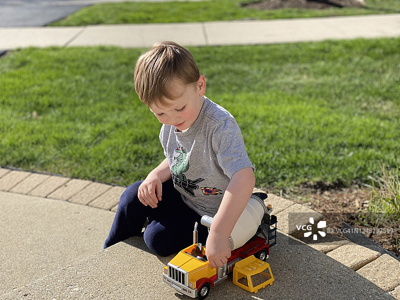 男孩在人行道上玩卡车图片素材