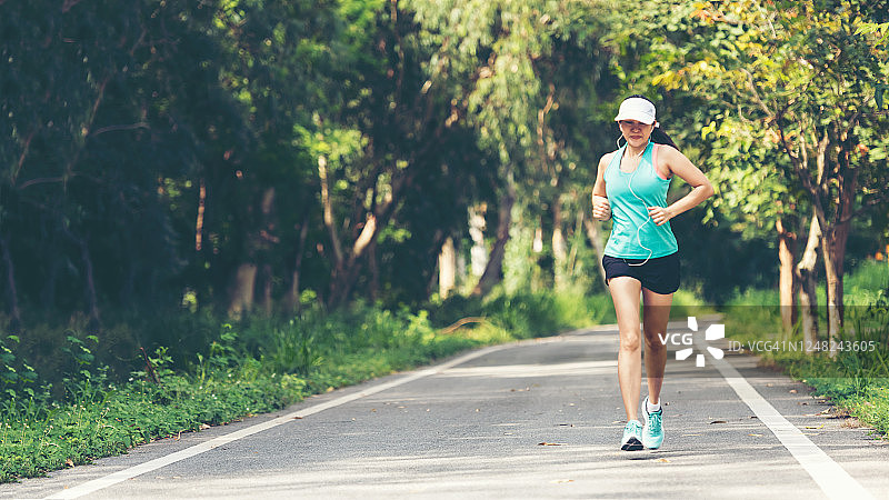 健康女人在户外公路上慢跑锻炼。亚洲跑步者在健身房锻炼，背景是自然公园。健康生活方式概念。图片素材