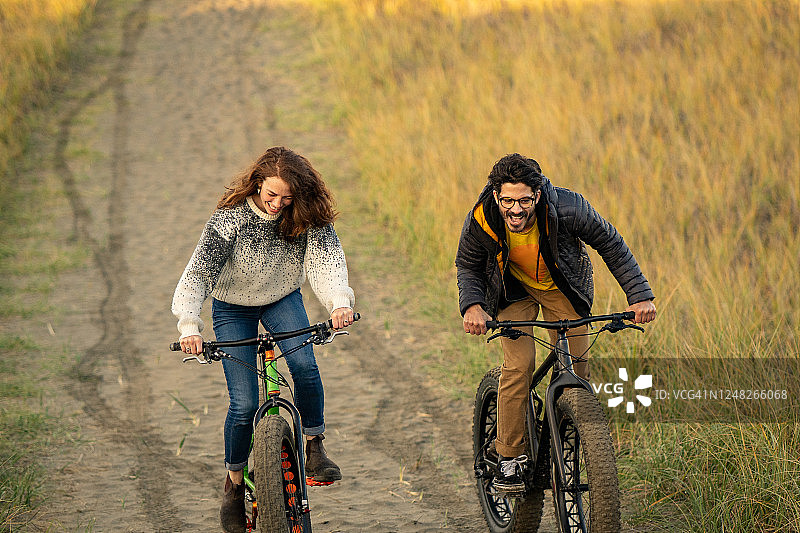 年轻情侣在沿海小路上骑胖胎自行车图片素材