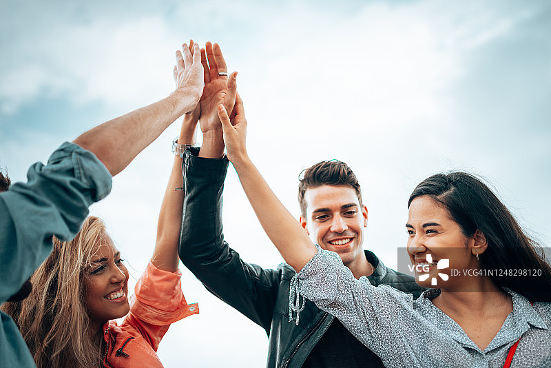 朋友们在户外齐心协力工作，举起手臂庆祝图片素材
