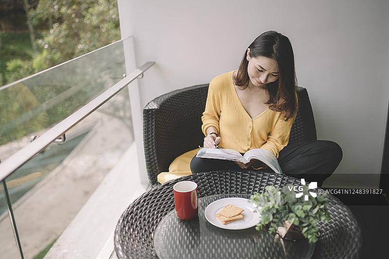 在阳台上放松身心、享受数字排毒时光的亚洲美丽女性图片素材