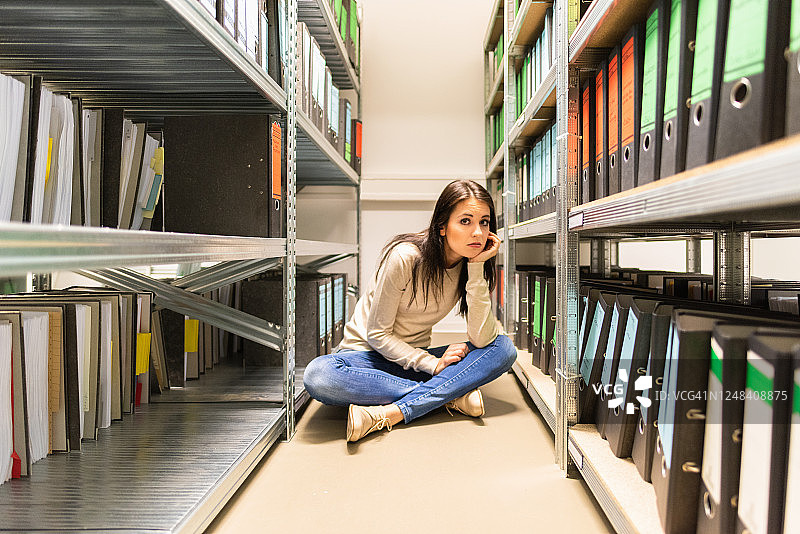 烦躁疲惫的女会计师坐在财务档案室里图片素材