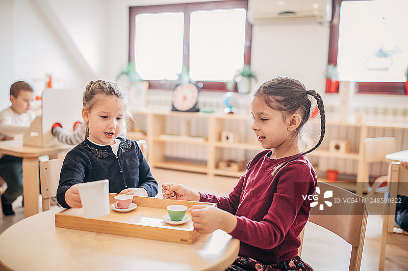 两个学龄前女孩玩过家家，像是在举行茶话会图片素材