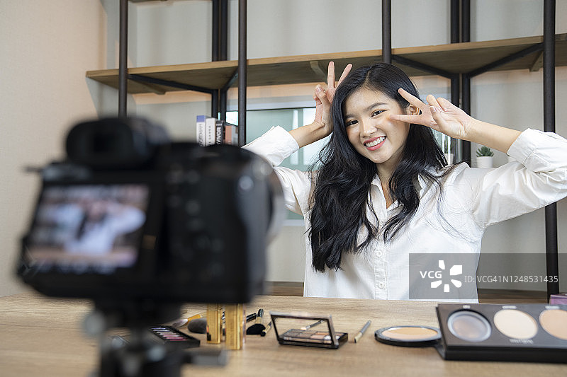 年轻亚洲女性时尚博主在家用数码相机直播图片素材
