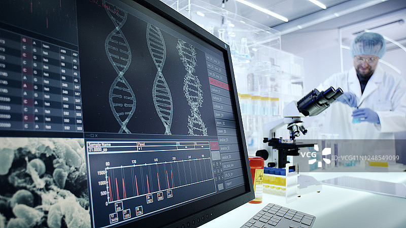 男子在实验室使用设备，电脑屏幕上的DNA研究图片素材