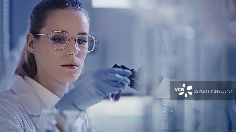 有魅力的女微生物学家在未来实验室使用显微镜进行研究图片素材
