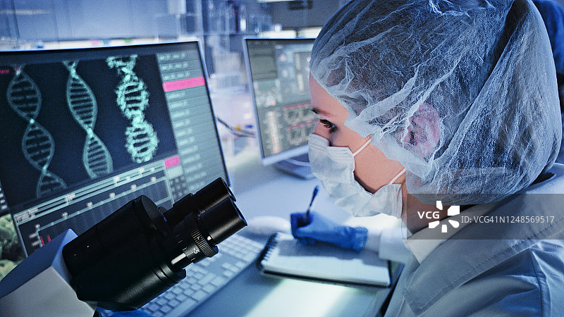 女医生研究DNA突变，前景是带有DNA螺旋的电脑屏幕图片素材