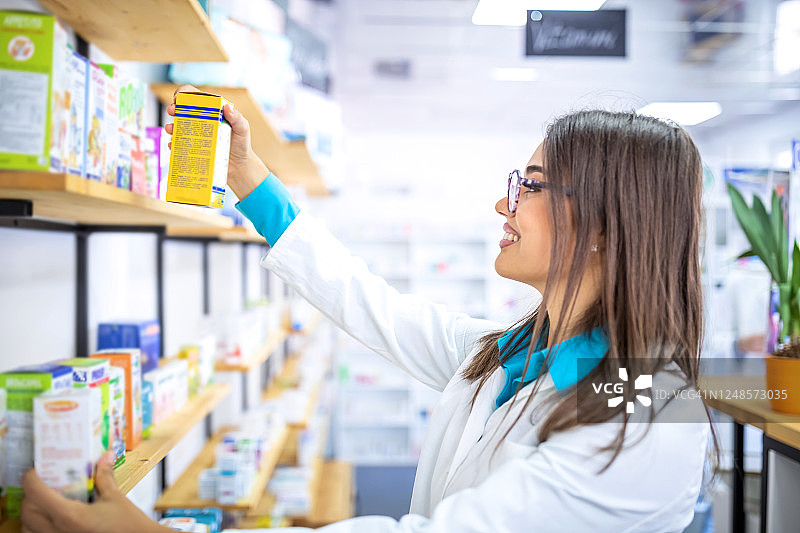 药剂师在药房工作：从货架取药图片素材