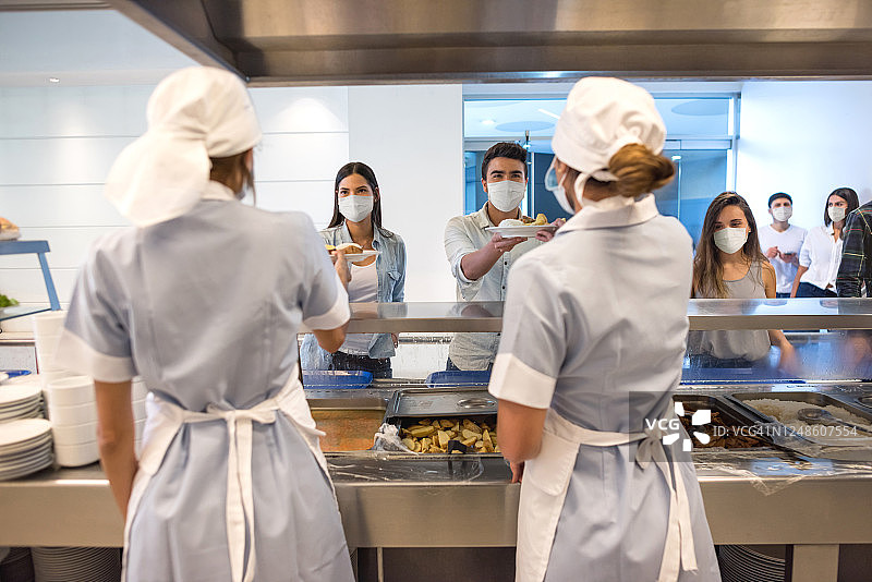 人们在自助餐厅用餐并戴着口罩图片素材