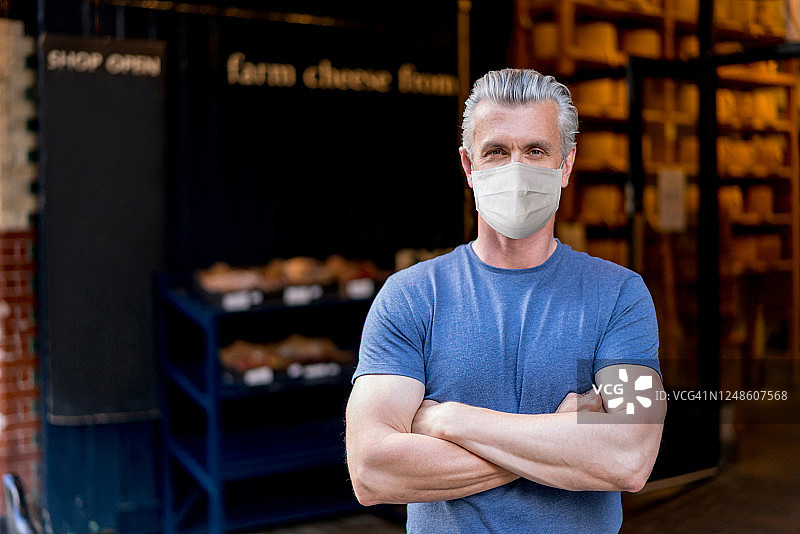 一位戴着口罩在奶酪店外面的企业主肖像图片素材