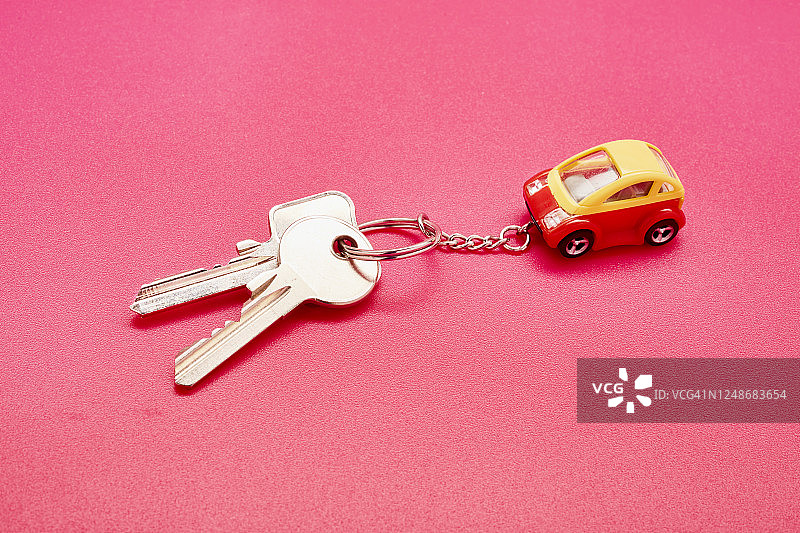 粉色背景上的钥匙扣和玩具车静物图片素材