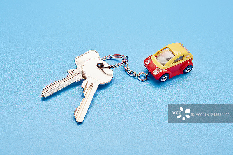 蓝色背景上的钥匙圈、钥匙和小玩具车静物图片素材