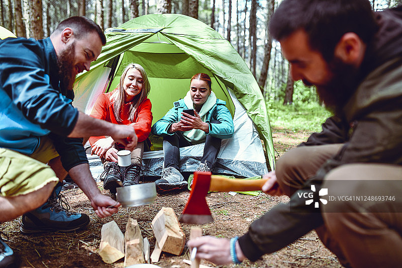 男人们在营地帐篷附近劈柴，女人们在旁图片素材