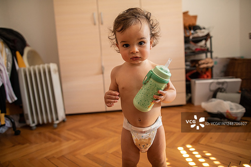 穿着尿布拿着奶瓶的可爱幼儿男孩图片素材