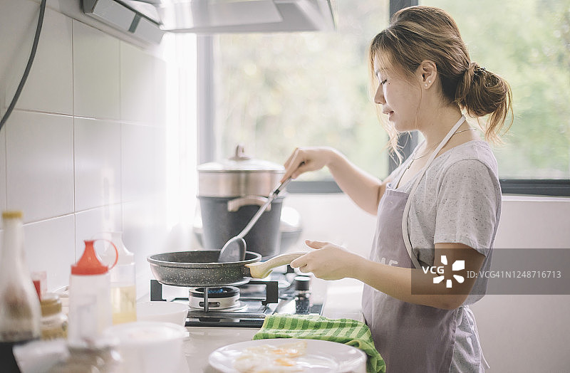 中国美女在厨房煎鸡蛋准备早餐图片素材