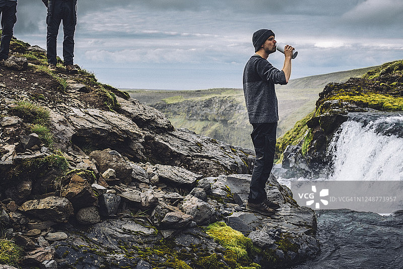 男人在冰岛兰德曼纳劳卡附近从河里喝水图片素材