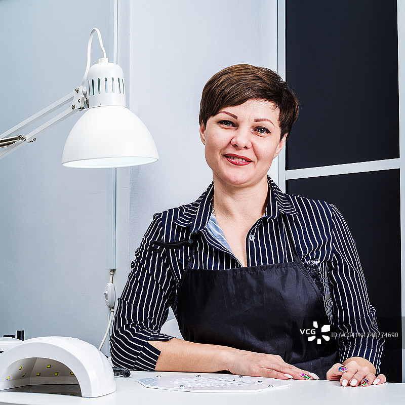 美甲沙龙里的女 работница，在工作场所等待顾客图片素材